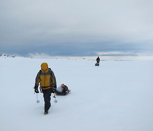 Gav walking towards camera with Stu in the background, both hauling sleds