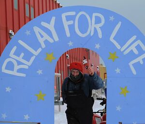 Relay for Life. Mark poses at hand-painted finish-line arch, with baton