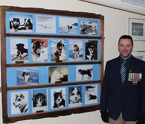 Jason Blackwell poses on ANZAC day with his medals and photos of the station huskies