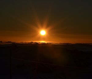 Sun at Casey with ground showing as black and sky is orange