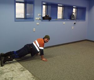 Dan in trades office doing what appears to be a push-up on the new flooring