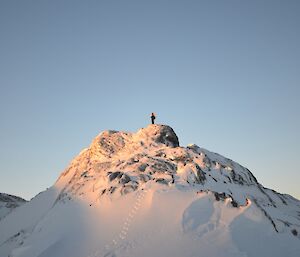 Snow covered mountain at Browning with expeditioner posed on top