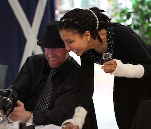 Jamie and Sheri sharing a laugh over a photo at midwinter dinner