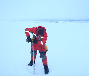Jamie drilling sea ice in Newcomb Bay