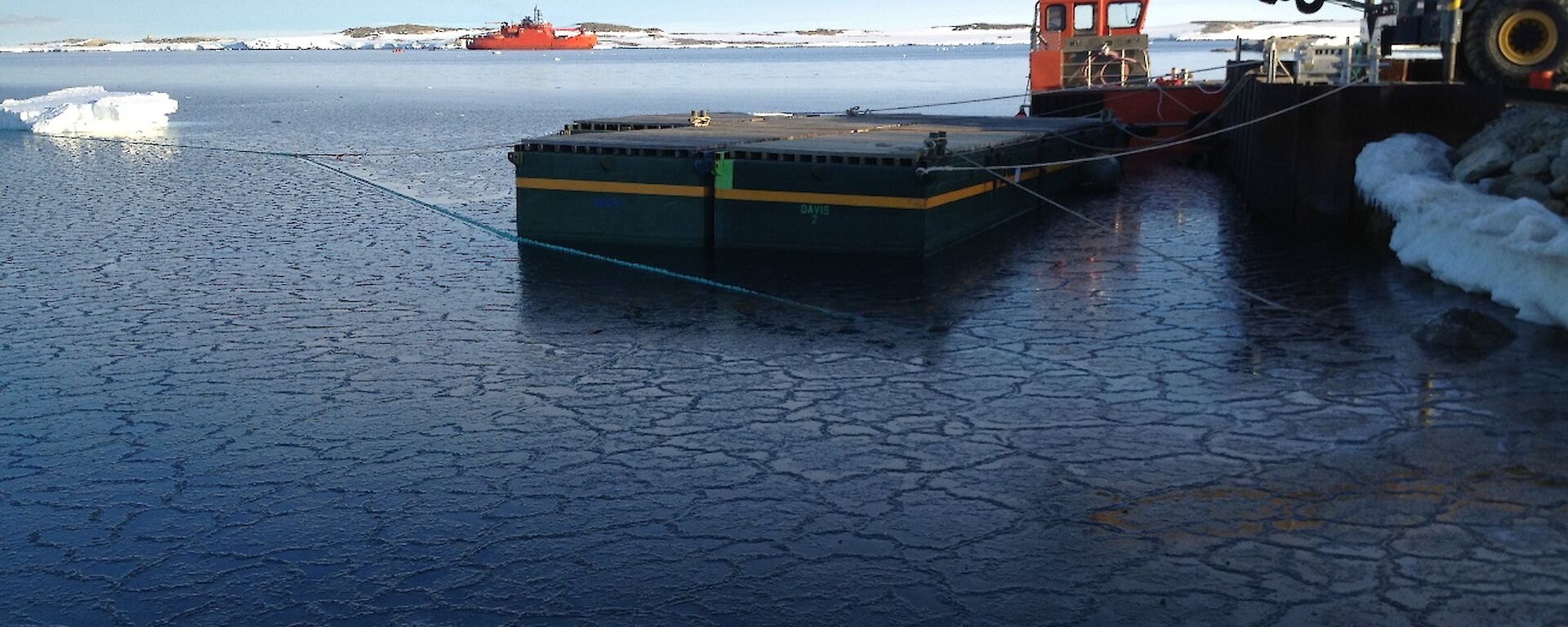 Photo shows a small floating pier awaiting resupply ship Aurora Australis, crane in right of photo