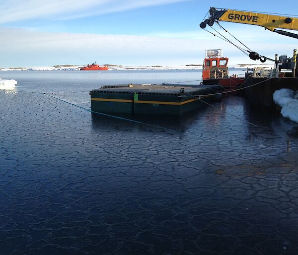 Photo shows a small floating pier awaiting resupply ship Aurora Australis, crane in right of photo