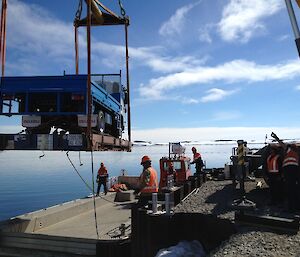 Flat bed truck being lifted by the crane ashore