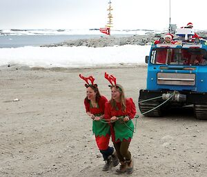 Jess and Bec dressed as reindeer, pulling Santa’s sleigh, aka a hagg