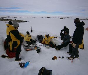 The group sitting around in the ice dug kitchen waiting for dinner to cook