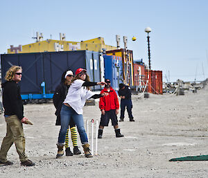 Jess pitching a cricket ball with expeditioners around her