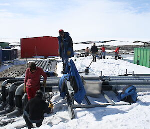 A number of French volunteers digging up snow and inspecting exposed cable trays