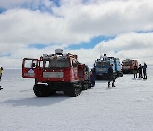 Three Hägglunds convoy with expeditioners outside stretching their legs