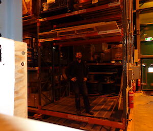 Expeditioner poses in warehouse standing on the bottom shelf of large storage area