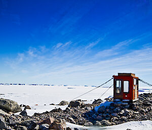 Jacks donga — a small dwelling atop rocks in Antarctic landscape and surrounded by snow