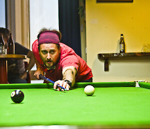 Ben in a low angle shot lining up pool cue and ball