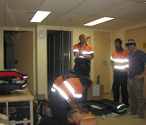 A group doing CPR on a dummy, while the other watch and observe