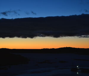 A sunset shot with low stratocumulus clouds in the middle of the frame, dividing the blue and orange colour of the sunsetting sky