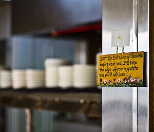 A sign with a diet advice hanging on the mess saying "Eat a bar of chocolate before each meal, It'll take the edge off your appetite and you'll eat less."