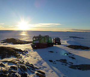 A green Hagglund traveling through some terrain