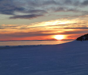 Sunset with different tone of red and yellow with blue sky and ice