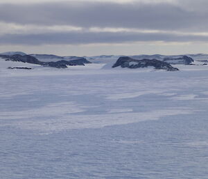 Landscape picture with flat white snowy terrain with rock ridges