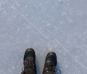 Over head shot of expeditioner standing on thick ice — shoes on ice