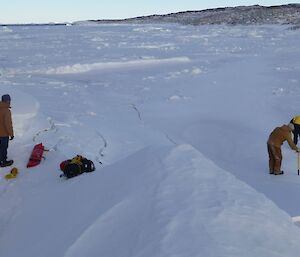 Male expeditioners drilling the sea ice to test the depth