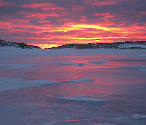 Bailey Peninsula — sunset over melt lake showing different shads of red, yellow and purple