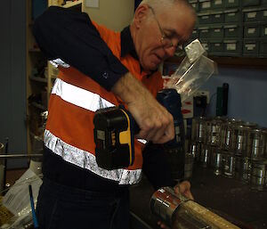 Expeditioner in a workshop drilling holes into metal cans