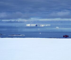 Aurora Australis anchored in Newcomb bay with Icebergs in the background and low clouds