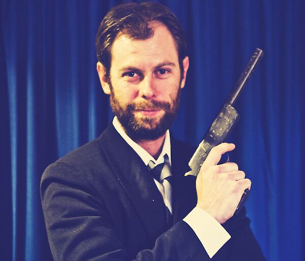 Aaron in a suit holding a toy gun