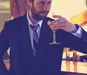 Aaron in a classic Bond Martini pose, Martini on hand, in a retro look photograph