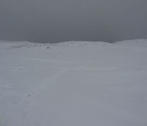 White snowy terrain and sea ice with low dark grey clouds
