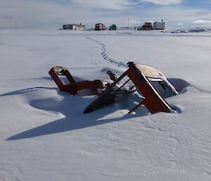 Remains of a tractor nearly covered with snow and Wilkes Hilton in the background