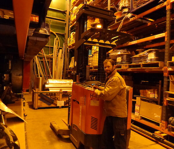 Aaron on the electronic fork lift in between two racks of the greenstore
