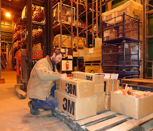 Aaron with boxes of equipment in the green store warehouse