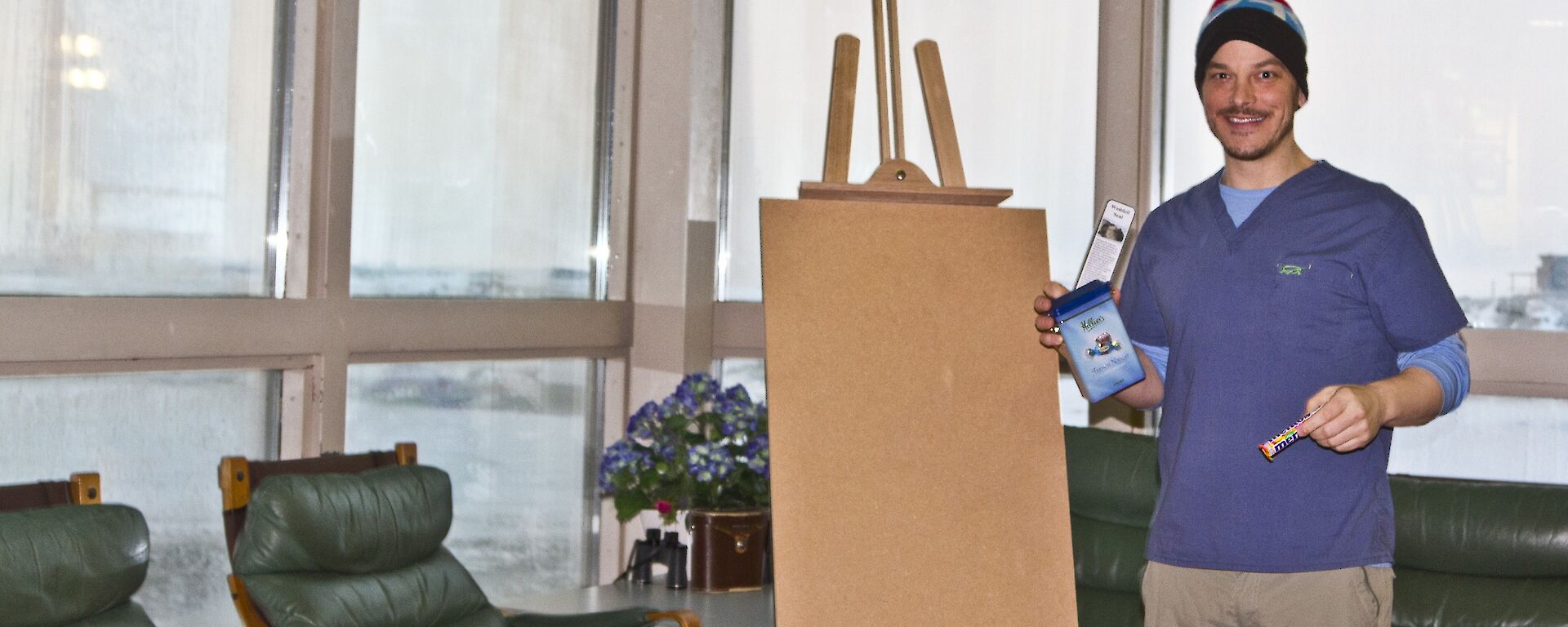 Chad posing with a hand full of chocolates and sweets, easel and a book mark