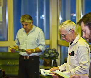 Allan in the background with Aaron and Doug in the foreground, all reading the ANZAC program