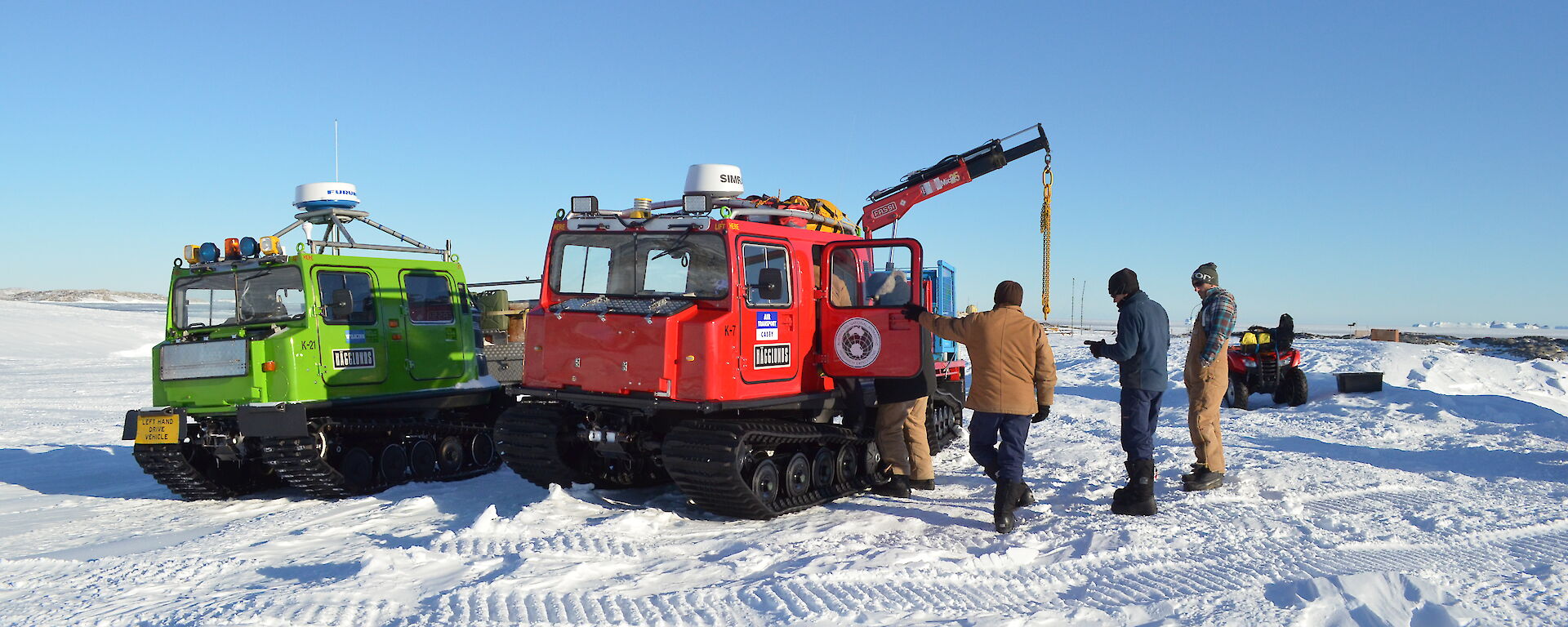 A number of expeditioners talking around a red Hägglunds