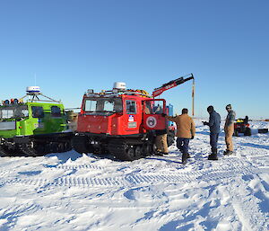 A number of expeditioners talking around a red Hägglunds