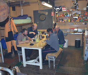 The four expeditioners inside the Wilkes hut having dinner
