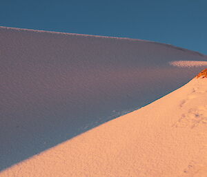 Blizz tail — a snowy hill in shadow covered in snow and ice from a blizzard