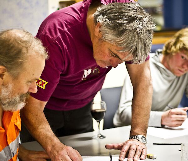 Allan leaning over the table to give instructions to Jukka