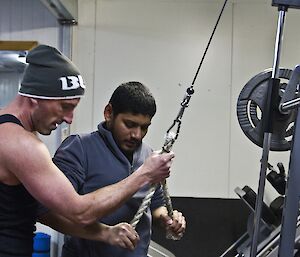 Lee teaching Abrar how to use a exercise machine