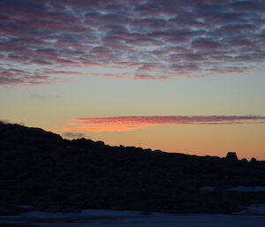 A colourful sunset behind a rocky hill