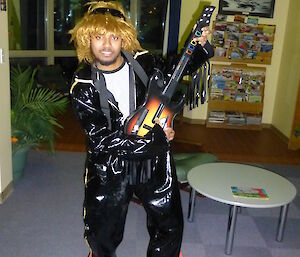 Abrar in a black leather Elvis suit in a classic Guitar hero pose