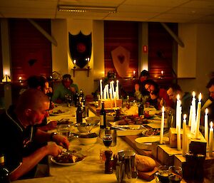 Candle lit room with a large dinning table with the expeditioners feasting on the spread of dishes