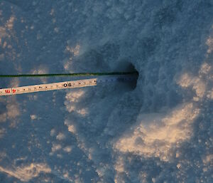 A drilled hole in the sea ice with a measuring tape