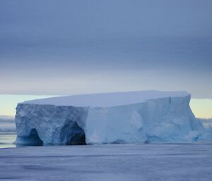 Large iceberg with a flat top and two cave like openings