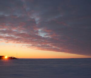 Sunrise over the skiway, a flat snow cover terrain with middle level clouds